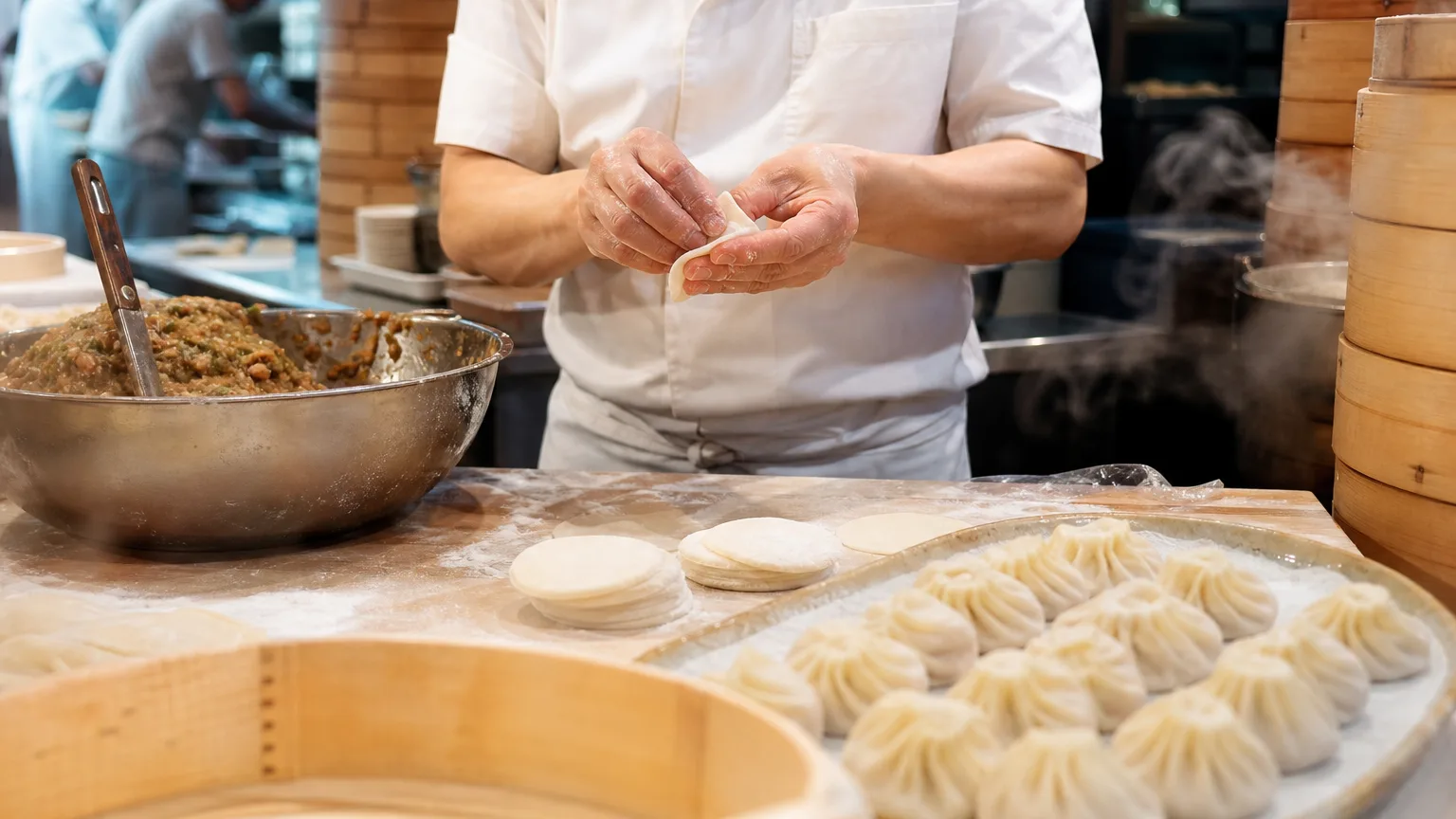 Dim sum restaurant table with bamboo steamers of dumplings and people dining in warm natural light.